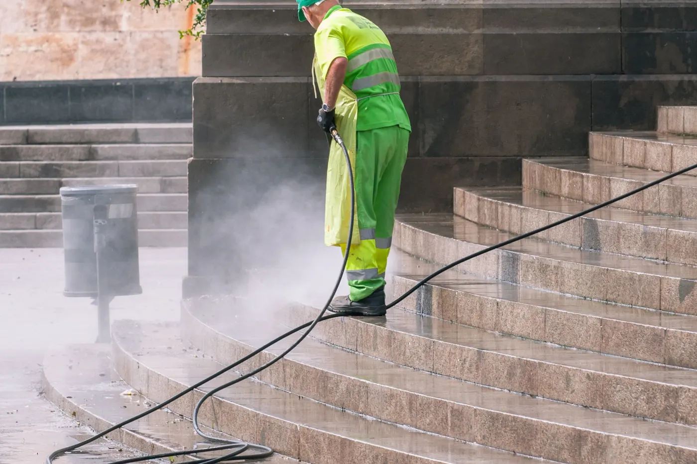 Stock photo of a worker pressure washing a set of stone steps